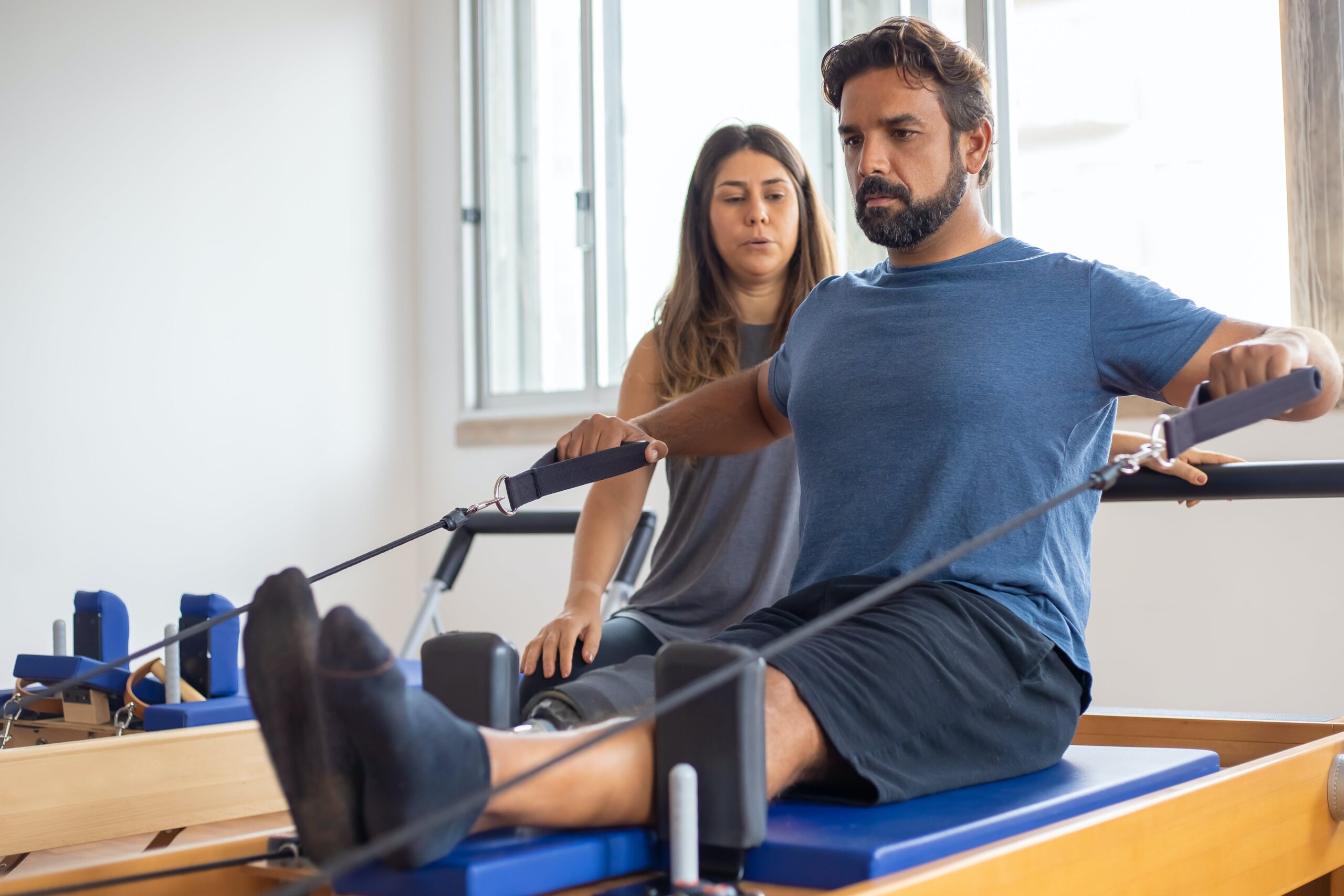 man doing physical exercise with help of trainer