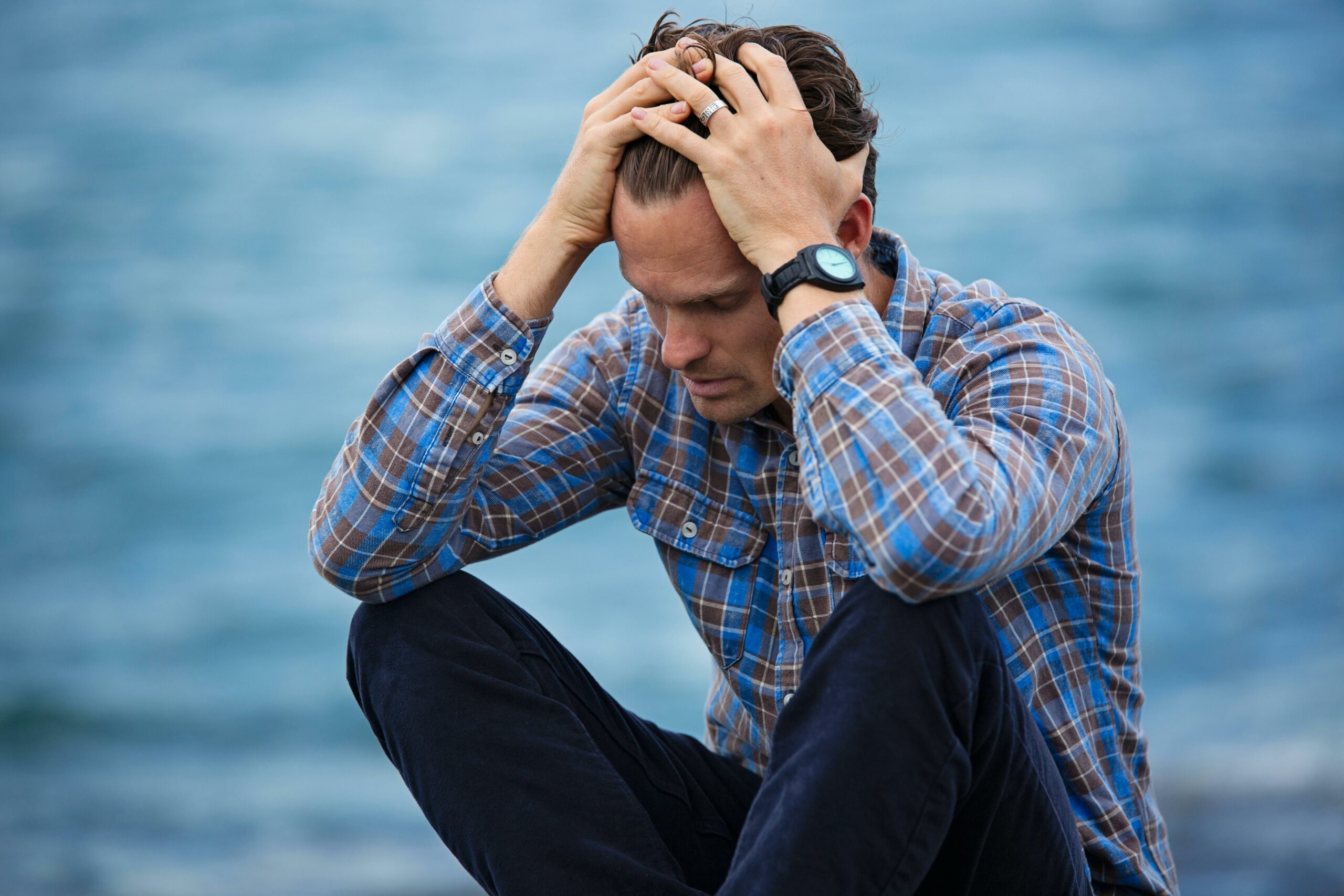 a man sitting by sea looking sad